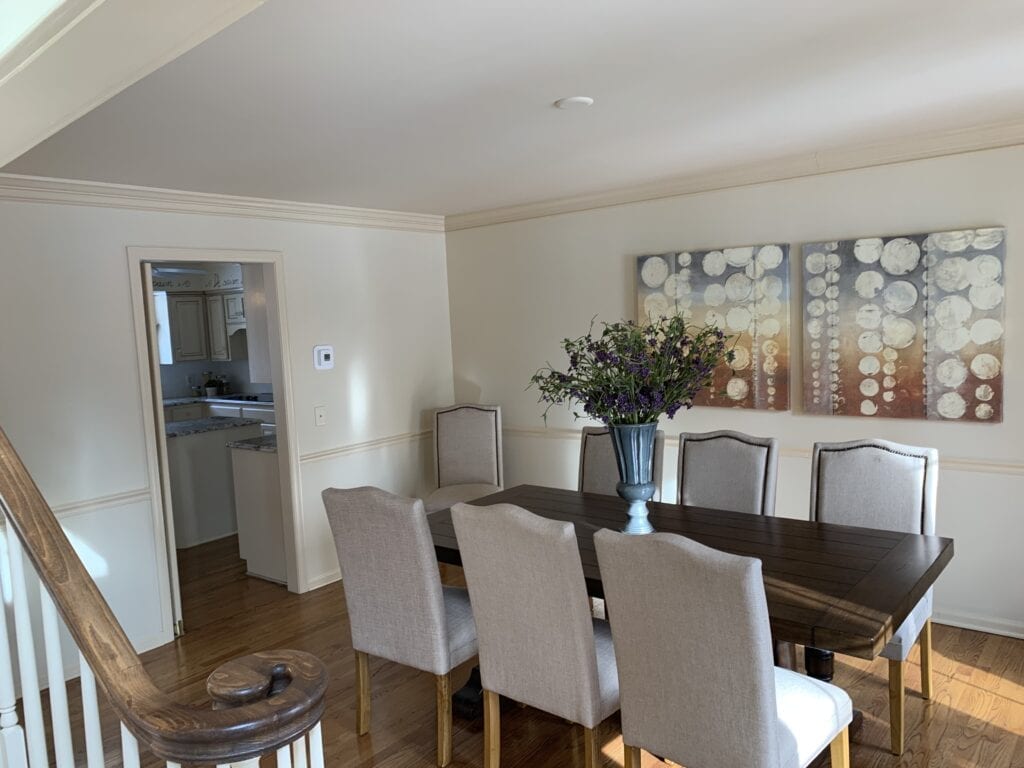 A dining room with a large table and chairs.