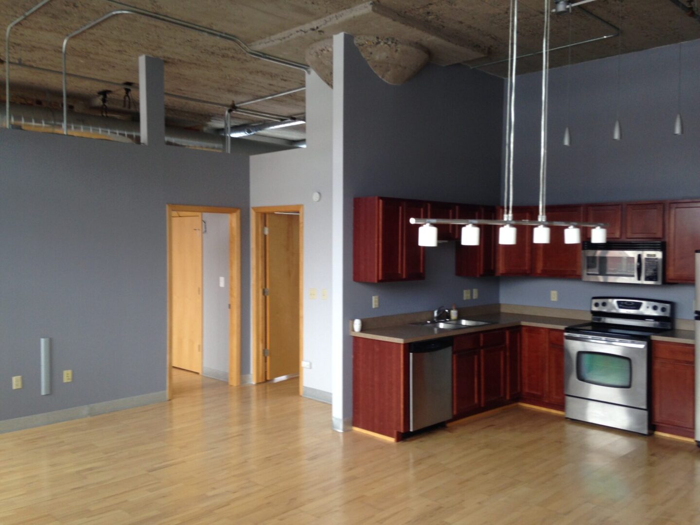 A kitchen with wood floors and stainless steel appliances.