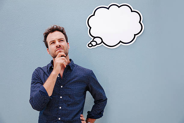 Pensive young man thinking, with thought bubble and space for your text, isolated on blue wall background